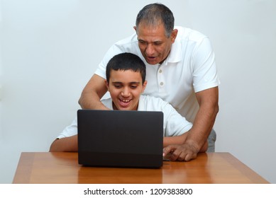 Senior Father And Teenage Son Using Laptop. Boy And Dad Sitting At Home Working With Tablet Computer.Happy Family Old Grandfather And Grandson On Laptop.Elderly Teacher Trainer And Teen Pupil Boy.