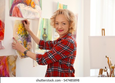 Senior Female Artist Hanging Picture In Studio