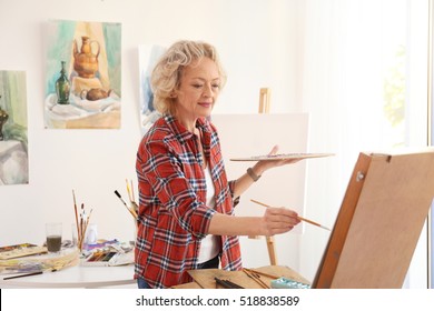 Senior Female Artist Painting Picture In Studio