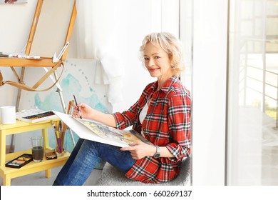 Senior Female Artist Painting Picture In Studio