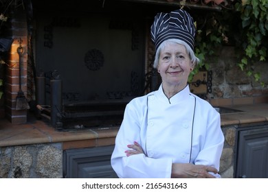 Senior female chef in traditional uniform