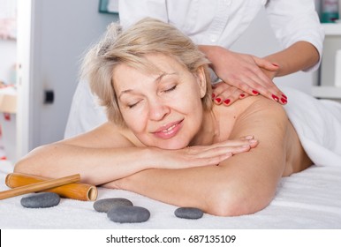 Senior female client enjoying relaxing massage in beauty salon