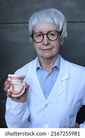 Senior Female Dentist Holding Denture Model