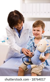 Senior Female Doctor Examining Happy Child, Smiling.