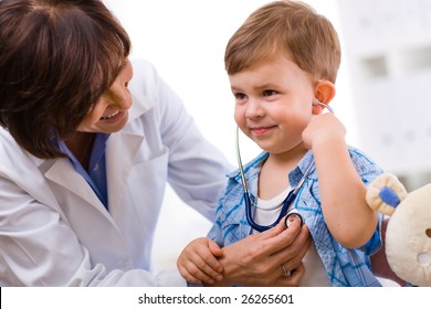 Senior Female Doctor Examining Happy Child, Smiling.