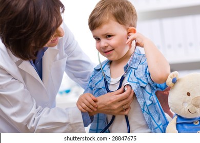 Senior Female Doctor Examining Happy Child, Smiling.