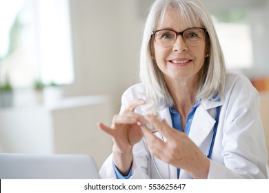 Senior Female Doctor Giving Prescription To Patient