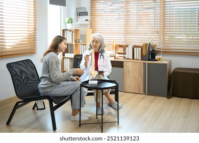 Senior female doctor pointing at vertebrae model while discussing spinal anatomy or treatment options with patient - Powered by Shutterstock