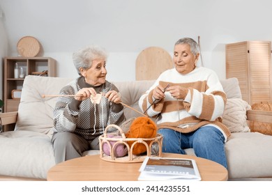 Senior female friends knitting on sofa at home - Powered by Shutterstock