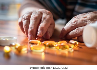 Senior Female Hands And Omega 3 Capsule On Table. Fish Oil Nutritional Supplement. Old Woman Taking Vitamin D Pills For Good Healthy. Medical Concept With People