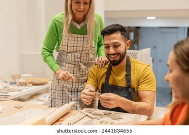 A senior female instructor and a male student share a joyful moment in a pottery class. - Powered by Shutterstock