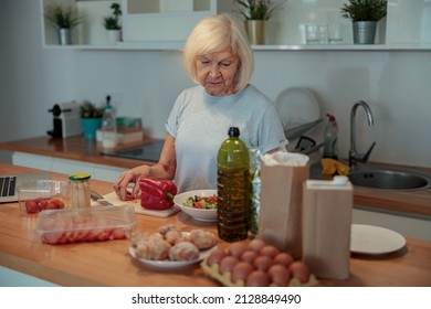 Senior Female Making Salad At Home Kitchen