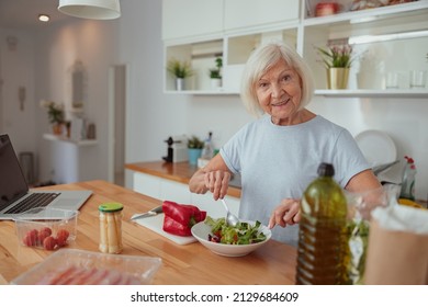 Senior Female Making Salad At Home Kitchen