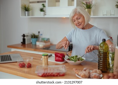 Senior Female Making Salad At Home Kitchen