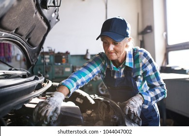 Senior female mechanic repairing a car in a garage. - Powered by Shutterstock