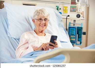 Senior Female Patient In Hospital Bed Using Mobile Phone