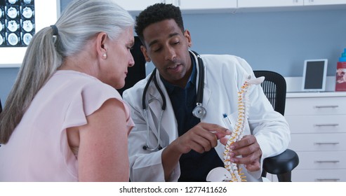 Senior female patient listening to doctor explain reason for her back pain - Powered by Shutterstock