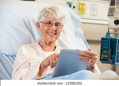 Senior Female Patient Relaxing In Hospital Bed With Digital Tablet