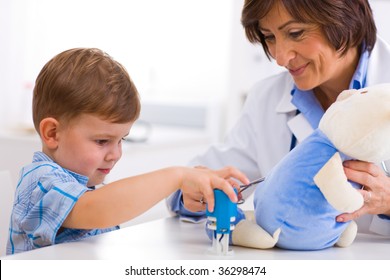 Senior Female  Pediatrician Playing With Child At Doctors Office.