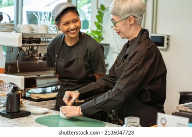 Senior Female Restaurant Owner Is Making Tea And The Smiling Asian Barista Is Happy To Work Together And Ready To Serve Drinks In The Coffee Shop.