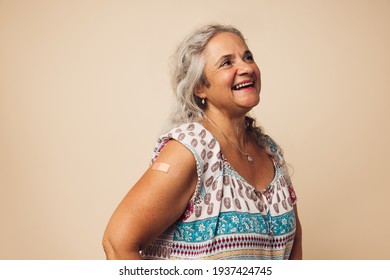 Senior female smiling after getting a vaccine. Woman looking away and smiling after receiving vaccination. - Powered by Shutterstock