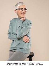 Senior Female Studio Portrait. Short Grey Hair Senior Model. Fashion Photography In Studio. Old Female Wearing Glasses. Confident Senior Female Portrait.