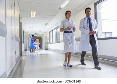 Senior weibliche Patientin im Rollstuhl im Krankenhauskorridor mit Krankenpflegern und Arzt