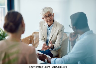 Senior financial advisor consulting a couple while having going through paperwork in the office. - Powered by Shutterstock