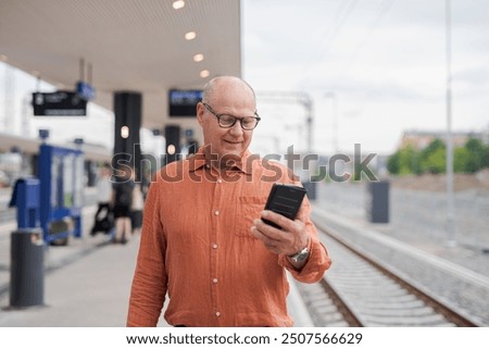 Senior Finnish Man Using Mobile Phone at Train Station Concept