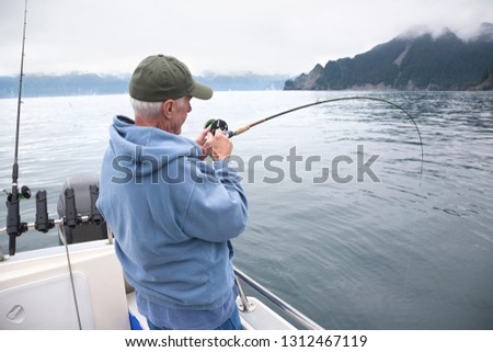 A senior fisherman fights a fish in the ocean near Seward, Alaska