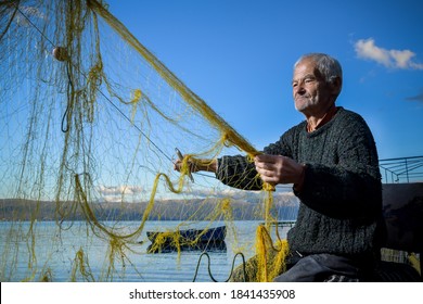 Senior fisherman holding fishing net near the beach. Fisherman hands close up. A fisherman preparing the fishing net