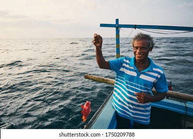 Senior fisherman holding red fish on fishing boat near coastline of Sri Lanka. - Shutterstock ID 1750209788
