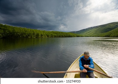 Senior Fisherman Rowing In A Boat On A Lake Mikkeljavre In Norway