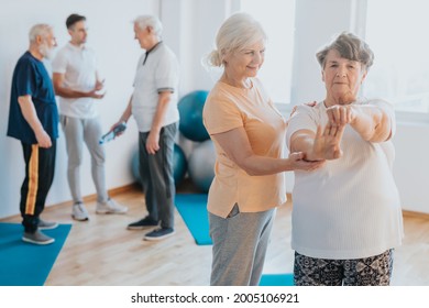 Senior Fitness Instructor Helping Older Woman With Stretching