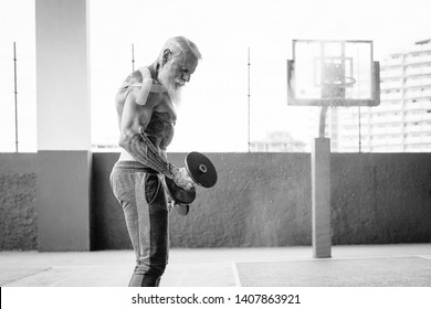 Senior Fitness Man Doing Biceps Curl Exercises Inside Old Gym - Fit Mature Male Training With Dumbbells In Wellness Club Center - Body Building And Sport Healthy Lifestyle Concept