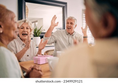 Senior friends, birthday celebration and party at a home with a present and gift with excited people. Surprise, singing and retirement of elderly group at a dining room table together with a smile - Powered by Shutterstock