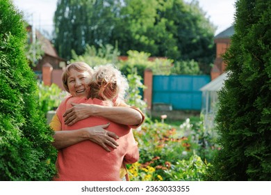 Senior friends, greeting and hug outdoor by house, funny and laughing together. Elderly women, handshake and embrace, happy and smile for bonding, care and welcome to retirement reunion in backyard - Powered by Shutterstock