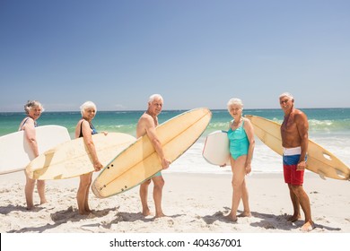 Senior friends holding surfboard on the beach - Powered by Shutterstock