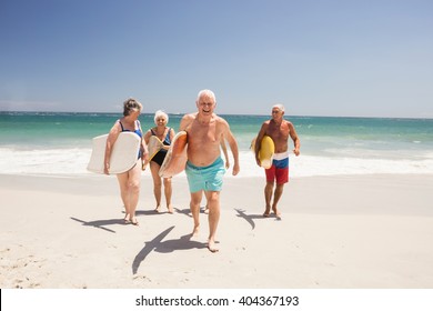 Senior friends holding surfboard on the beach - Powered by Shutterstock