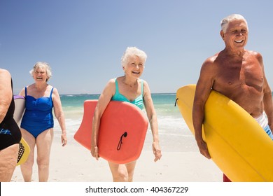 Senior friends holding surfboard on the beach - Powered by Shutterstock