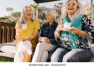 Senior friends laughing happily while having tea