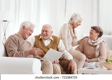 Senior Friends Are Laughing And Talking Together While Using Laptop