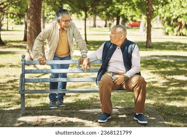 Senior friends, men and relax at park bench, talk and bonding outdoor with phone. Elderly people sitting together in garden, communication and serious conversation in nature for retirement in spring - Powered by Shutterstock