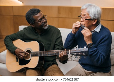 Senior Friends Playing Music With Acoustic Guitar And Harmonica