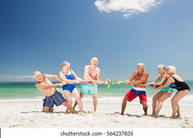 Senior friends playing tug of war on the beach - Powered by Shutterstock