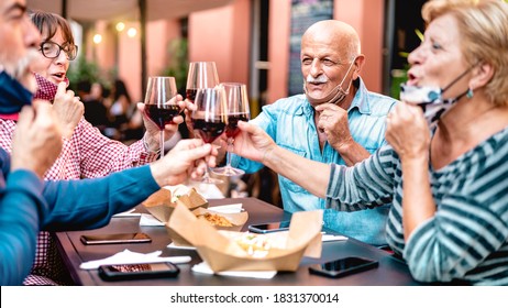 Senior Friends Toasting Wine At Restaurant Bar Wearing Opened Face Mask - New Normal Lifestyle Concept With Happy Mature People Having Fun Together At Garden Party - Warm Filter With Focus On Bald Man