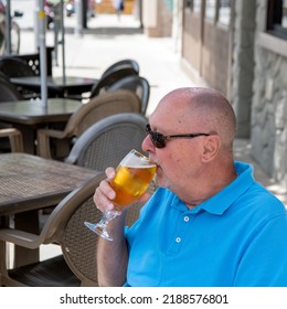 Senior Gay Man Drinking Beer On An Outside Patio.