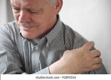 senior gentleman grimaces at the pain in his shoulder