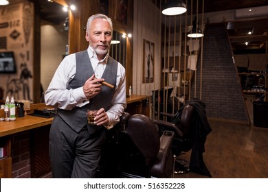 Senior gentleman standing with glass and cigar