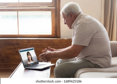 Senior grandfather sit on sofa quarantine at home speak talk on video call with smiling granddaughter, elderly grandparent use laptop go online communicate on Webcam conference with family